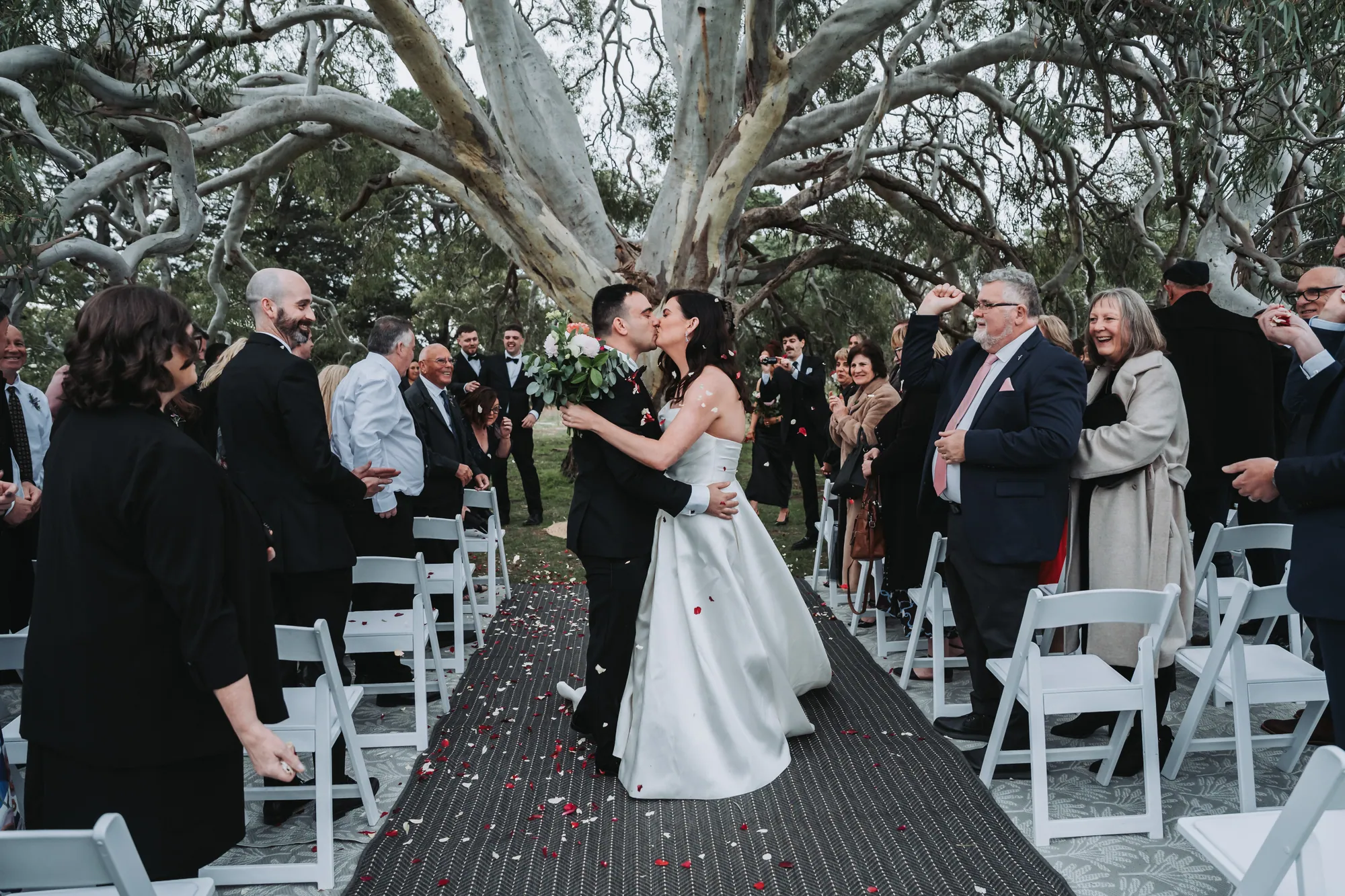 Kayla and Marko kissing in the aisle beneath the gums at Rocklea Farm