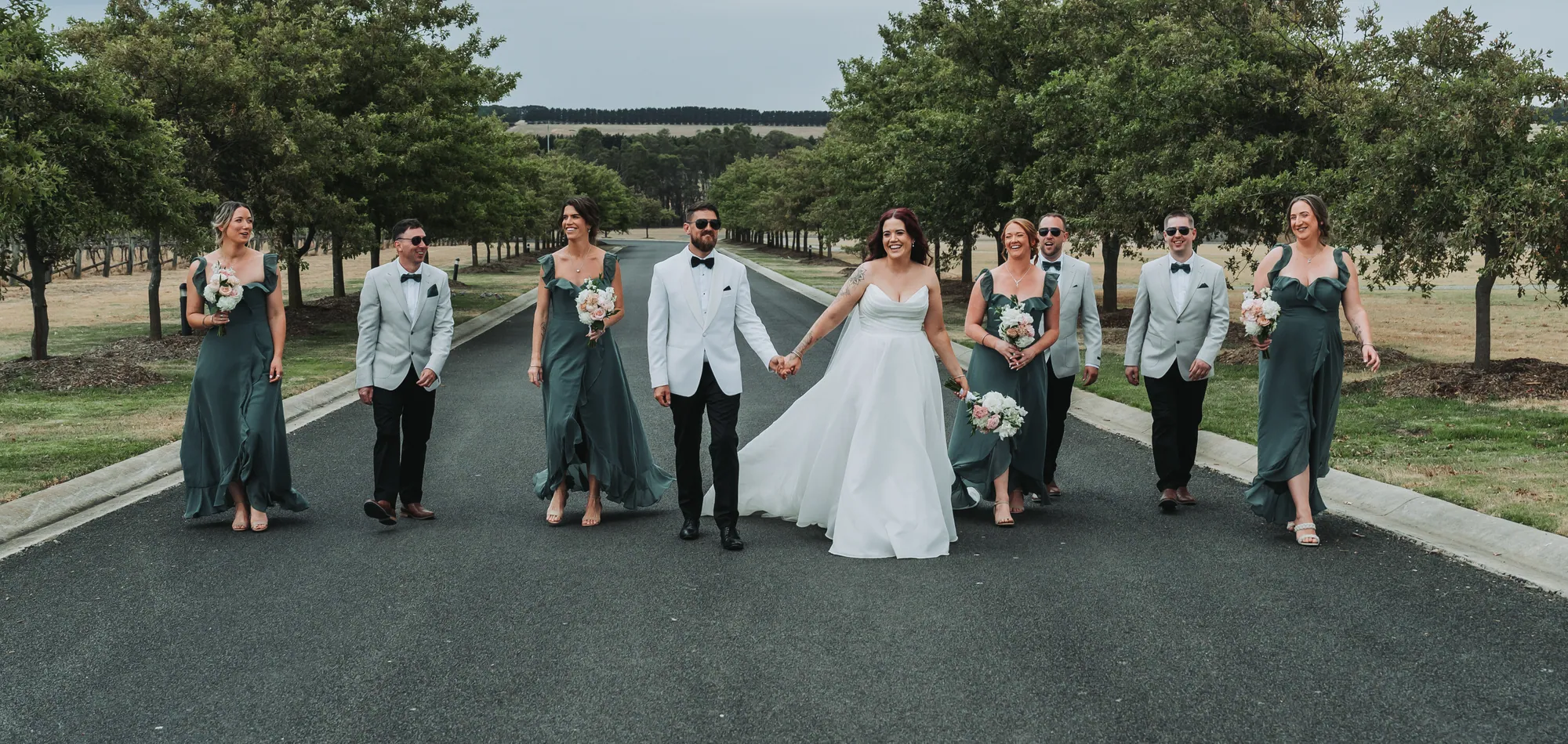 Steph and Chris with their bridal party on the vineyard road at Mount Duneed Estate